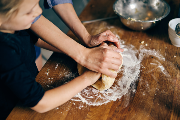 picture of an adult helping a child knead bread